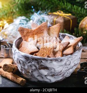 Schüssel mit hausgemachten Weihnachten Shortbread Stern Form Zucker Cookies anders Größe mit Zuckerpulver und Ausstechformen auf altem Holz Oberfläche mit Christma Stockfoto