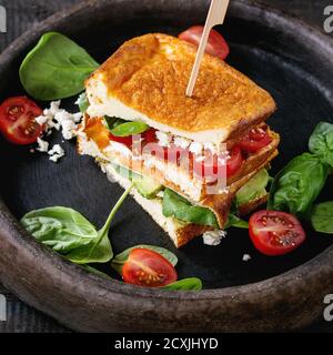 Low-carb Glutenfrei Cloud Brot vegetarisches Sandwich mit Spinat, Avocado, Fetakäse, Tomaten und Pesto, auf Lehm Fach über dem alten Holz Hinterg serviert. Stockfoto