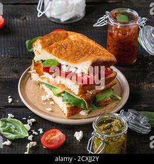 Kohlenhydratarme glutenfreie Cloud Bread Veggie Sandwich mit Spinat, Avocado, Feta-Käse, Tomaten und Pesto-Sauce, serviert auf dem Teller mit Gläsern Zutat Stockfoto