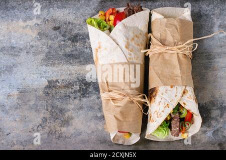 Mexikanisches Abendessen. Zwei tapeierte Tortillas Burrito mit Rind und Gemüse auf altem texturierten Zinnhintergrund. Flach liegend mit Kopierplatz Stockfoto