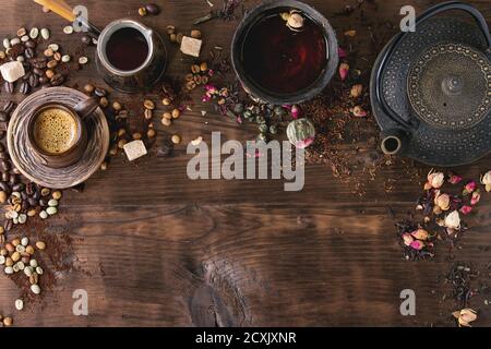 Essen Hintergrund Tee und Kaffee Thema. Verschiedene schwarze und grüne trockene Tee, verschiedene Kaffeebohnen, Tasse heißen Tee und Kaffee, Teekanne über dunklem Holz b Stockfoto