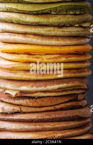 Hoher Stapel von bunten hausgemachten amerikanischen Ombre Schokolade, grünem Tee Matcha und Kurkuma Pfannkuchen. Nahaufnahme. Hintergrund für das Essen. Stockfoto