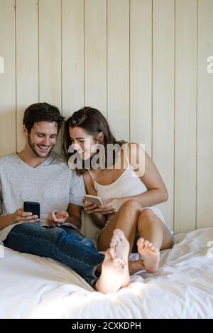 Junges Paar mit Smartphones im Schlafzimmer Stockfoto