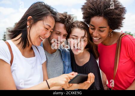 Glückliche junge Freunde, die Fotos auf dem Smartphone ansehen Stockfoto
