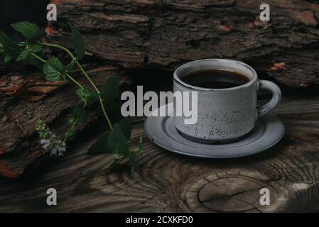 Eine Tasse Espresso auf einem Holztisch auf dunklem Hintergrund. Zweig der frischen Minze in der Nähe. Stockfoto