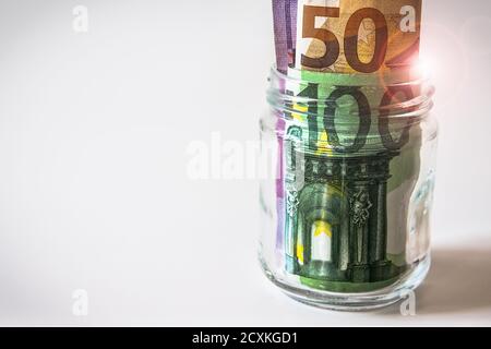 Glasglas mit Euro-Banknoten isoliert auf weiß. Stockfoto