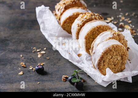 Satz von hausgemachtem Eis sandwiches in Hafer-Kekse mit Mandeln Zucker Krümel, Blaubeeren und Minze auf Backpapier über dunkle Metall Textur Hintergrund. Stockfoto