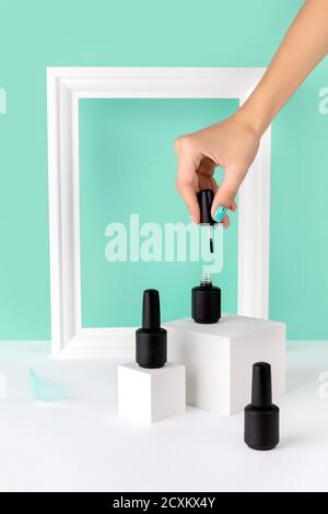 Flasche Nagellack auf Podium mit Womans Hand auf Türkis Stockfoto