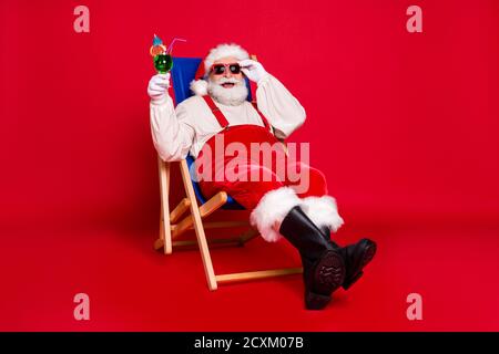 Portrait von seinem er schön gut aussehend fröhlich fröhlich froh bärtig Fat Santa Vater Hipster sitzt im Stuhl Chill out trinken mojito hat Spaß isoliert Stockfoto