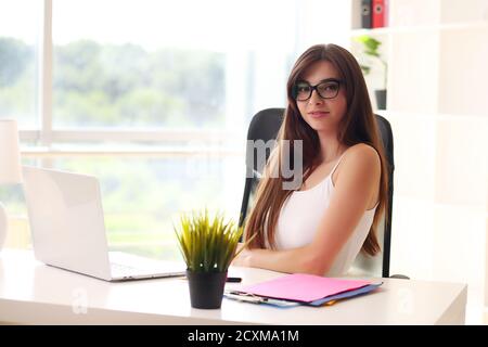 Schöne Geschäftsfrau nutzt einen Laptop und lächelt während der Arbeit im Büro Stockfoto