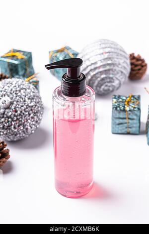 Gesicht waschen rosa Gel für Gesicht Make-up saubere, flüssige Seife in Kunststoff-Spender-Flasche in der Nähe von Weihnachten Neujahr Ornamente und Spielzeug Stockfoto