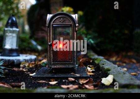 Alte Grablaterne mit brennender Kerze in der Dämmerung auf einem Friedhof im Herbst Stockfoto