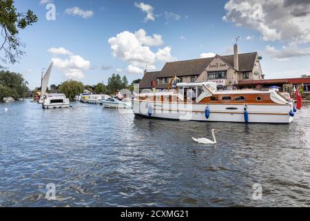 Boote fahren auf dem Fluss Bure vorbei am Ferry Inn Public House, Horning, Norfolk Broads, England Stockfoto