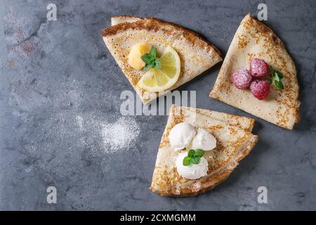 Süße Crêpes Pfannkuchen mit verschiedenen Füllungen frische Himbeeren, Zitroneklumpen, Mascarpone Käse, Minze, Puderzucker über grau blau Metall Textur backgr Stockfoto