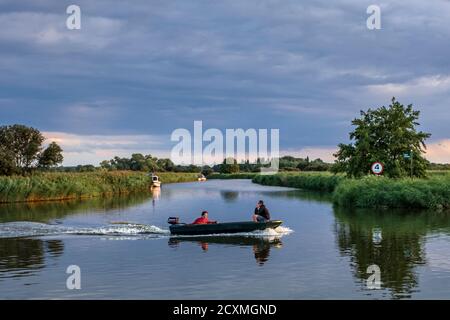 Ein Motorboot, das entlang des Flusses Bure in der Nähe von St. Benet's Abbey, Norfolk Broads segelt. Stockfoto