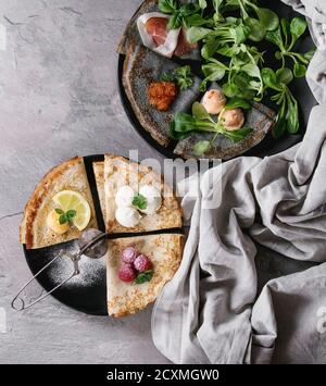 Vielzahl von schwarzen und weißen Krepp Pfannkuchen mit verschiedenen süß- und Salzwasser füllen. Rotem Kaviar, Fisch Pastete, Schinken, grüner Salat, Himbeeren, Zitroneklumpen, mas Stockfoto