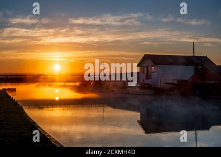 Blick von der historischen Brücke in Potter Heigham an einem nebligen Sommermorgen, Norfolk Broads. Stockfoto