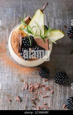 Dessert Frühstück geschichteten Chia-Samen, Schoko-Pudding, Reis Brei aus Glas dekoriert mit frischen Brombeeren, in Scheiben geschnitten Birne, Kakaopulver. Stehen mit Stockfoto