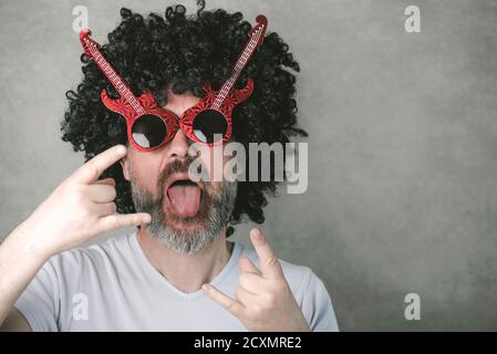 Lustige Mann mit Sonnenbrille tun Rock-Symbol mit Händen nach oben Vor grauem Hintergrund Stockfoto