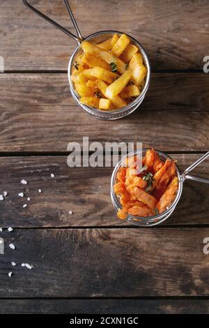 Auswahl an pommes Frites traditionelle Kartoffeln, Süßkartoffeln, Karotten serviert in Frittierkorb mit Salz, Thymian auf altem Holzhintergrund. Draufsicht mit Stockfoto