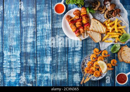 Vielzahl von Grill-Snack-Lunch. Platten vom Grill, pikante Garnelen Spieße, Huhn, Schweinefleisch, Gemüse, Pilze-Spieße, Brot, Pommes frites Kartoffeln mit Saucen Stockfoto