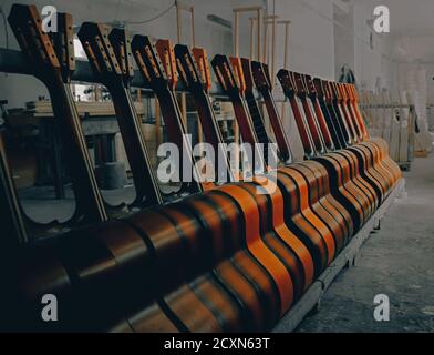 Akustische Gitarren stehen in Reihen. Nahaufnahme der Gitarren in einer Reihe bei Workshop, Musik Instrumental Konzept. Geringe Schärfentiefe. Stockfoto