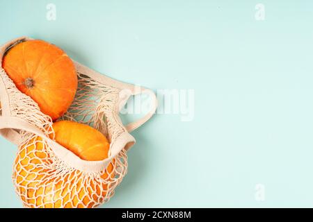 Kürbisse im Saiteneinkaufbeutel auf Holzhintergrund. Platz für Text kopieren. Halloween, Thanksgiving oder saisonal herbstlich. Design-Modell Hintergrund Stockfoto