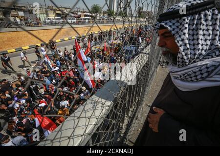 Bagdad, Irak. Oktober 2020. Ein Iraker sieht zu, wie Demonstranten zum ersten Jahrestag der regierungsfeindlichen Demonstrationen protestieren. Quelle: Ameer Al Mohammedaw/dpa/Alamy Live News Stockfoto