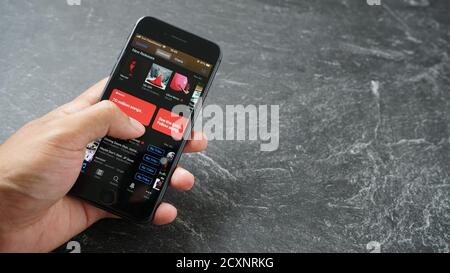 Mataram, Indonesien - 1. Oktober 2020: Hand hält Apple iPhone 8 mit Apple itunes Musik-App auf dem Bildschirm auf Stein Pad, Draufsicht. Stockfoto