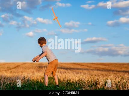Happy Kind läuft mit Spielzeug Flugzeug auf Himmel Hintergrund glücklich Familie Konzept. Kindheitstraum Stockfoto