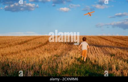 Happy Kind läuft mit Spielzeug Flugzeug auf Himmel Hintergrund glücklich Familie Konzept. Kindheitstraum Stockfoto