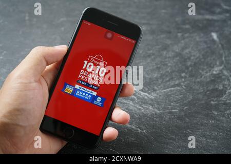 Mataram, Indonesien - 1. Oktober 2020: Hand hält Apple iPhone 8 mit shopee Marktplatz Online-Shop auf dem Bildschirm auf Stein Pad, Draufsicht. Stockfoto