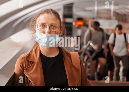 Eine Frau in der falschen medizinischen Maske steht in der U-Bahn. Die Schutzmaske wird nicht richtig auf dem Gesicht einer Frau beim Transport getragen Stockfoto