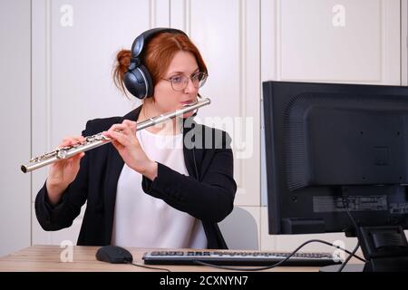 Ein Musiklehrer führt eine Lektion über das Spielen eines Musikinstruments über das Internet durch. Flötenunterricht online und online Musikunterricht während Quarantäne Stockfoto