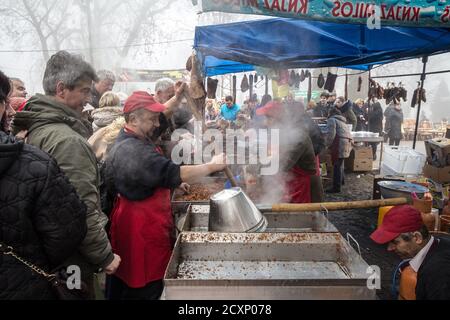 KACAREVO, SERBIEN - 18. FEBRUAR 2017: Mann, der Cvarci in einem Topf auf einem Markt von Kacarevo kocht. Cvarci, oder cvarak, sind typische Schweinefleisch Rinden aus dem Fett von t Stockfoto