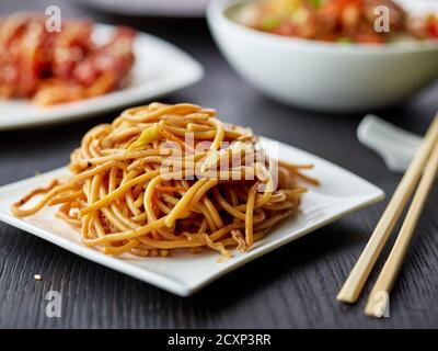 Teller gebratene Nudeln mit Gemüse auf Restauranttisch, chinesische Küche Stockfoto