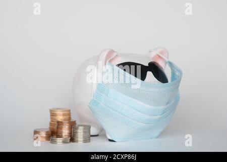 Der Zusammenbruch der Finanzmärkte und die Gefahr für finanzielle Ersparnisse aufgrund eines Pandemie-Virus.Masked Sparschwein Stockfoto