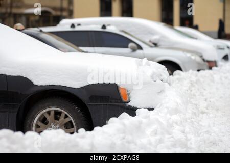 Autos auf einer Seite der Stadt Straße mit Schnee im Winter geparkt. Stockfoto