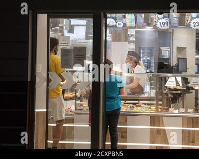 BELGRAD, SERBIEN - 22. SEPTEMBER 2020: Weibliche Angestellte, Bakter, die Kunden in einer Bäckerei mit einer Atemmaske in Belgrad während des coron bedienen Stockfoto