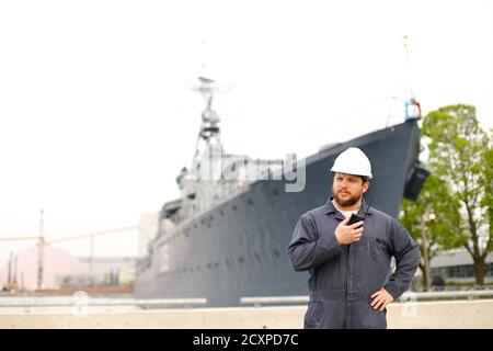Marine Chief Mate im Gespräch mit Walkie Talkie Radio und in der Nähe von Offshore-Schiff in Background. Stockfoto
