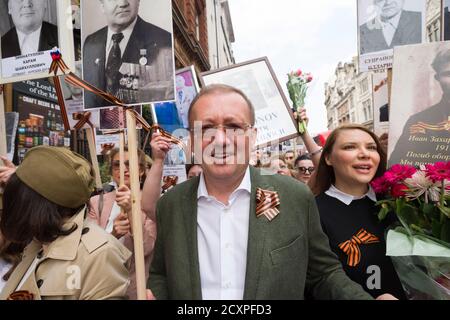 Botschafter der Russischen Föderation in Großbritannien, Alexander Wladimirowitsch Jakowenko, (grüne Jacke und Brille) führt, die London Marsch des Immortal Regiment, Der marsch soll russischen Männern und Frauen gedenken, die im Zweiten Weltkrieg gekämpft haben und in Russland und anderen Ländern am 9. Mai im Rahmen der Feier des Siegestages stattfinden. Während der Märsche tragen die Menschen Fotos ihrer Verwandten, die am Krieg teilnahmen. Etwa 12 Millionen Menschen nahmen 2015 an den Märschen des Immortal Regiments in ganz Russland Teil. Der Londoner marsch begann von der Nordterrasse des Trafalgar Square, direkt vor dem Stockfoto