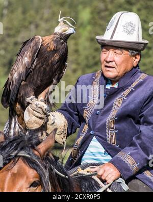 Issyk Kul, Kirgisistan - Mai 28, 2017 - Adler Jäger hält sich die Adler auf dem Arm vor der Jagd Stockfoto