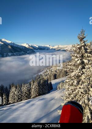 Landschaftlich schöne Aussicht auf schneebedeckte Berge im Skigebiet Von Saalbach Hinterglemm in den österreichischen alpen unter einer Decke Von Wolken gegen blauen Himmel in der Stockfoto