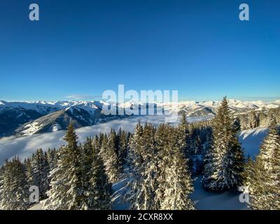 Landschaftlich schöne Aussicht auf schneebedeckte Berge im Skigebiet Von Saalbach Hinterglemm in den österreichischen alpen unter einer Decke Von Wolken gegen blauen Himmel in der Stockfoto