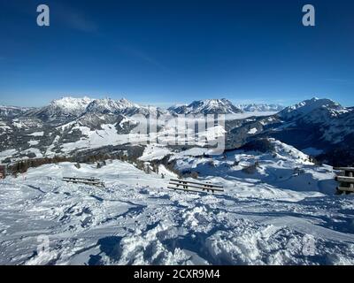 Landschaftlich reizvolle Aussicht auf schneebedeckte Loferberge (links), Leoganger Berge und Skipisten von Fieberbrunn in den Australischen alpen vor blauem Himmel Stockfoto