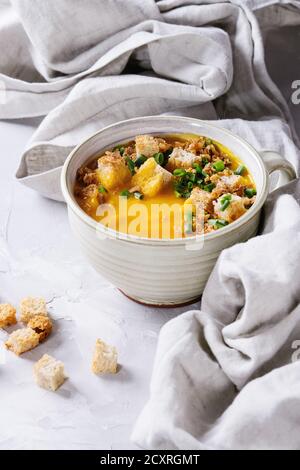 Becher vegetarische Kürbis-Karottensuppe mit Croutons und Zwiebel auf textiler Serviette auf grauem Betongrund. Nahaufnahme Stockfoto