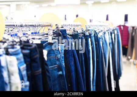 Eine Reihe von Damen Denim-Hosen auf einem Kleiderbügel im Geschäft. Verkauf von Jeans im Geschäft. Selektiver Fokus. Stockfoto