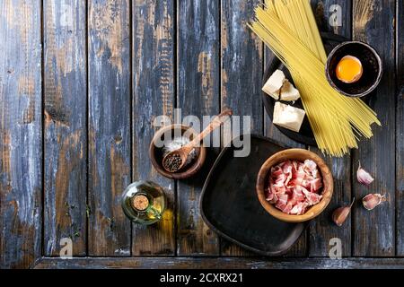 Zutaten für traditionelle italienische Pasta alla Carbonara. Ungekochte Spaghetti, bauchspeck Speck, Parmesan, Eigelb, Salz, Pfeffer in Olivenholz bo Stockfoto