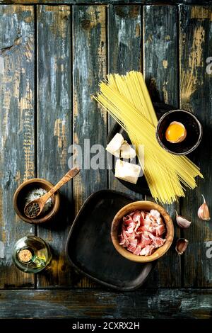 Zutaten für traditionelle italienische Pasta alla Carbonara. Ungekochte Spaghetti, bauchspeck Speck, Parmesan, Eigelb, Salz, Pfeffer in Olivenholz bo Stockfoto