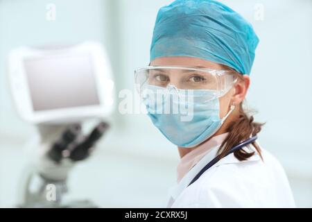 Mikrobiologin in einer Schutzmaske, die Sie anschaut. Stockfoto